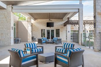 an outdoor patio with blue and white chairs and a television